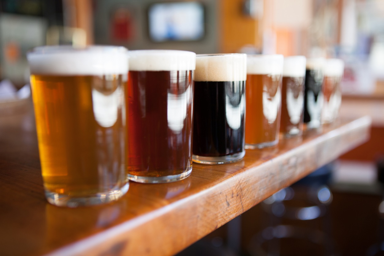 Row of different beers in glasses on a wooden bar